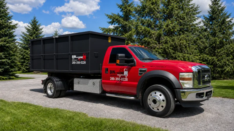 Bin and Gone red truck carrying a black rental bin.